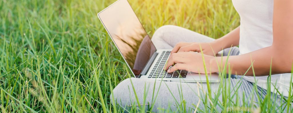 close-up of young woman using laptop at meadows.