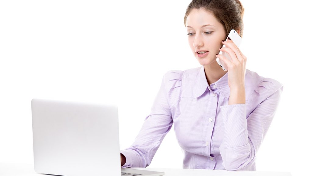 Young girl talking on smartphone and typing on laptop