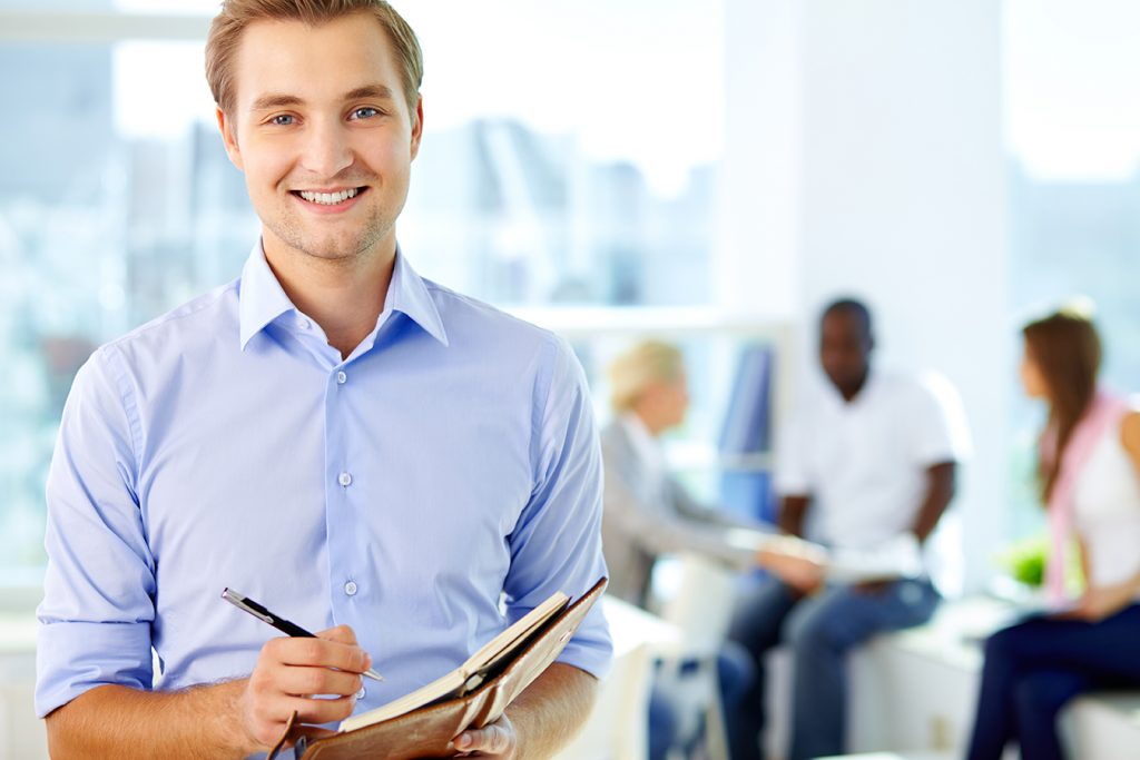 Portrait of a young business guy writing in his organizer