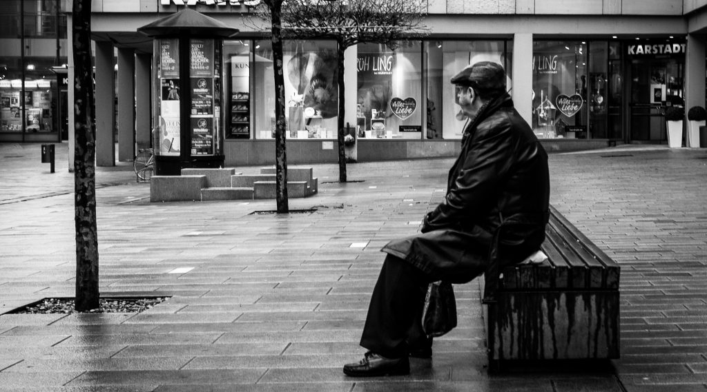 Man sitting alone on a bench in the rain