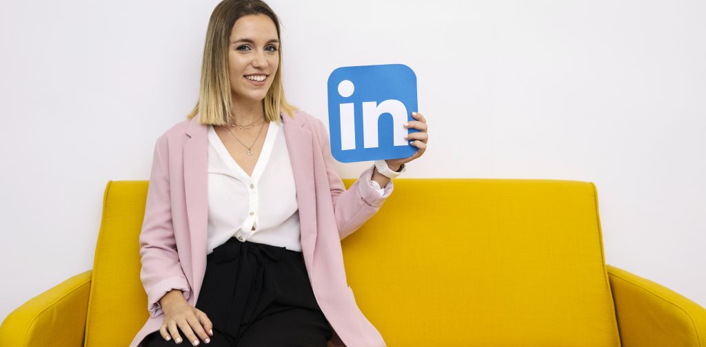 Woman sitting on sofa holding linkedin icon