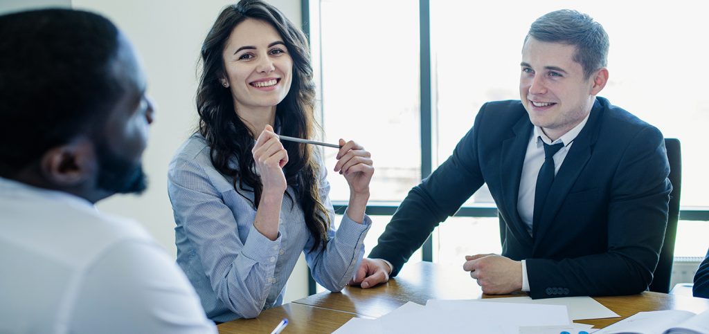 Three businesspersons in a meeting, all smiling