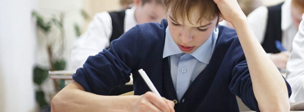 Young boy struggles with homework in classroom