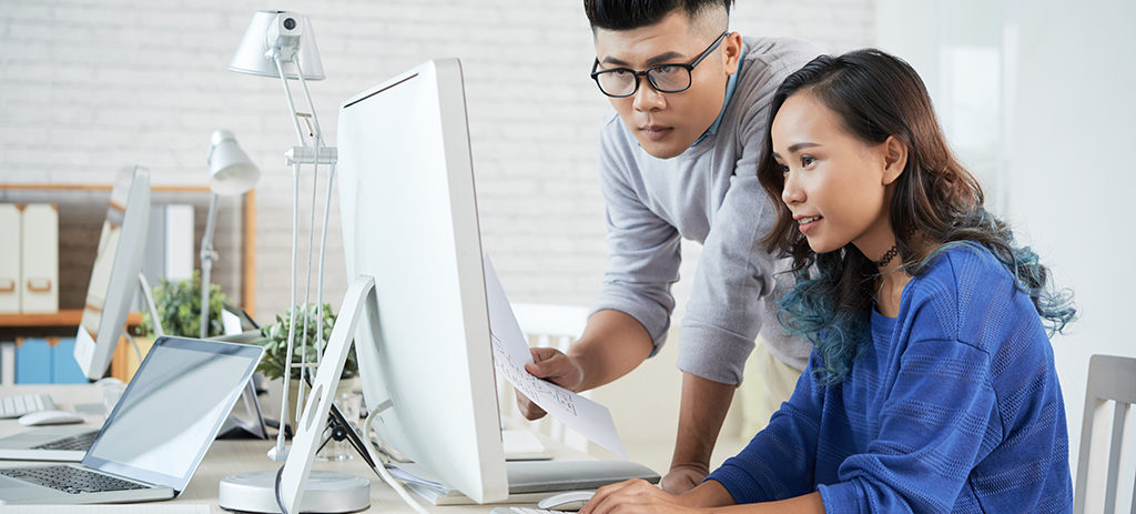 Two colleagues discussing presentation on computer at office