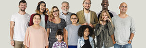 A diverse group of smiling adults and children. Some of whom are talking on cell phones.