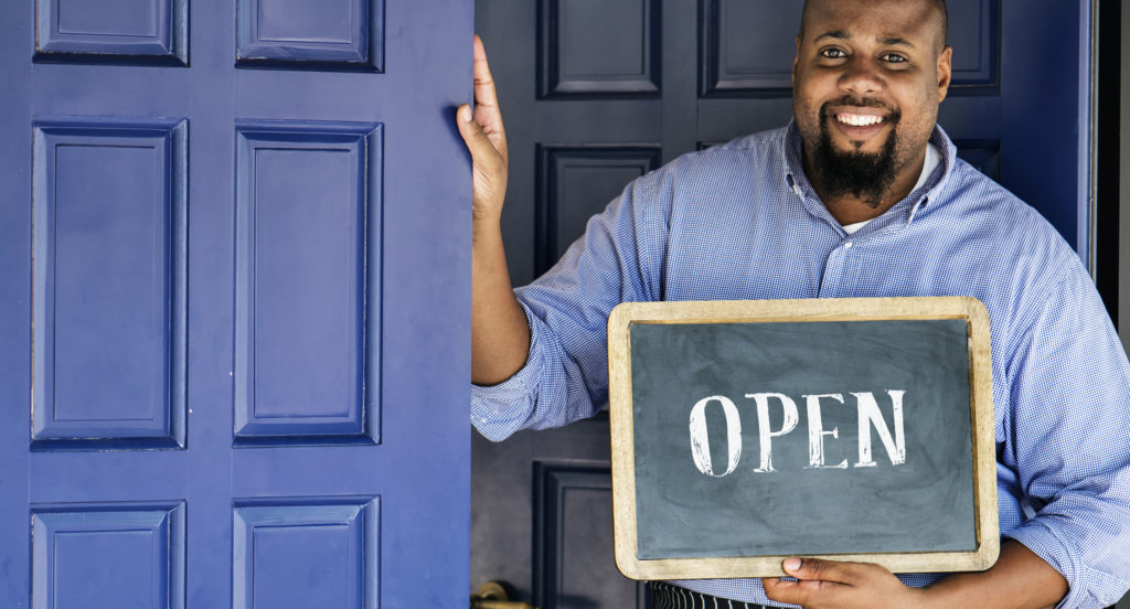 A cheerful small business owner with open sign